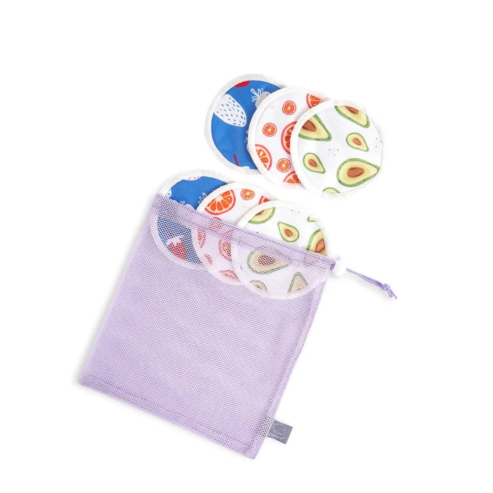 A lavender mesh drawstring bag containing several round reusable pads with printed avocado, strawberry, and citrus patterns on a white background.