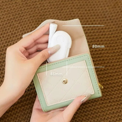 Small green and beige wallet with measurements on a brown textured background